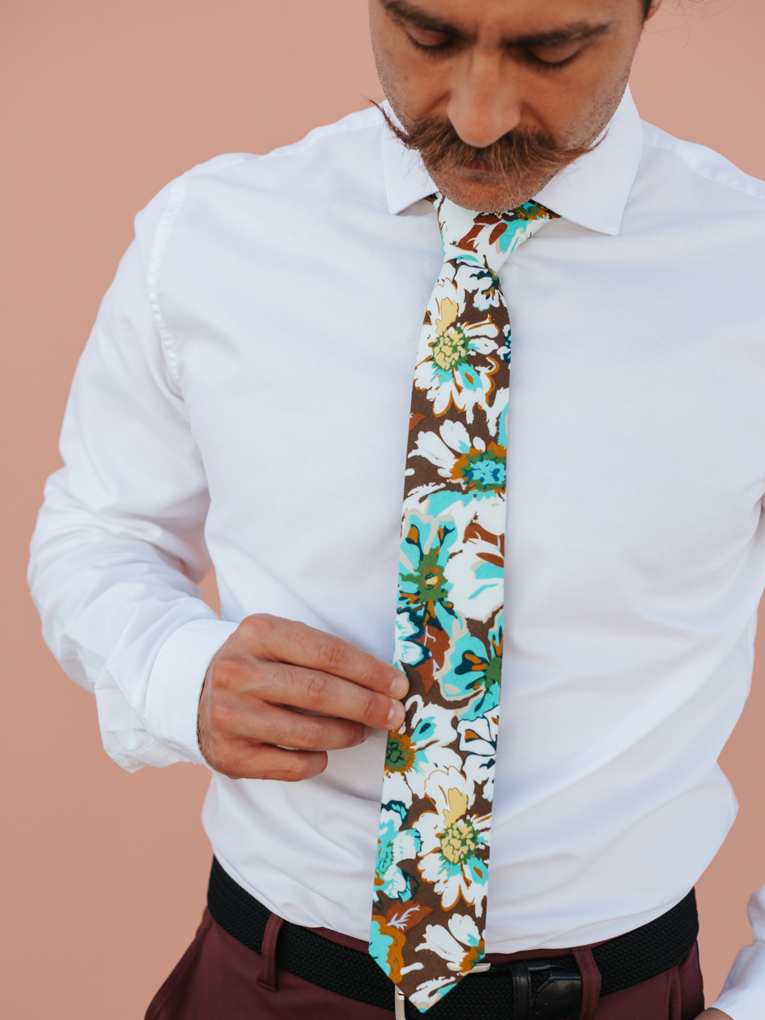 A close up of a man wearing a brown, yellow, and blue flower cotton skinny tie for weddings, grooms, and groomsmen.