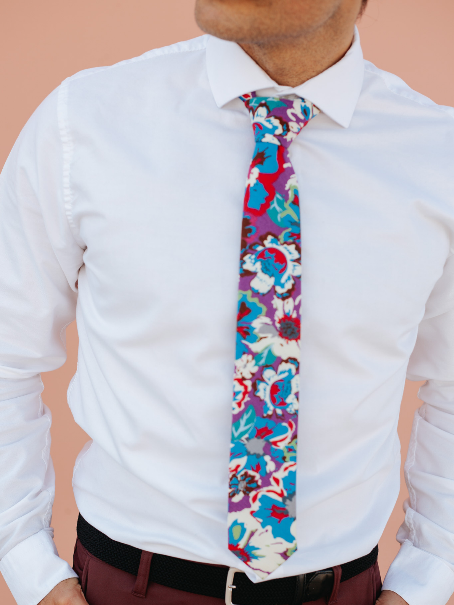 A close up of a man wearing a purple and blue flower cotton skinny tie for weddings, grooms, and groomsmen.