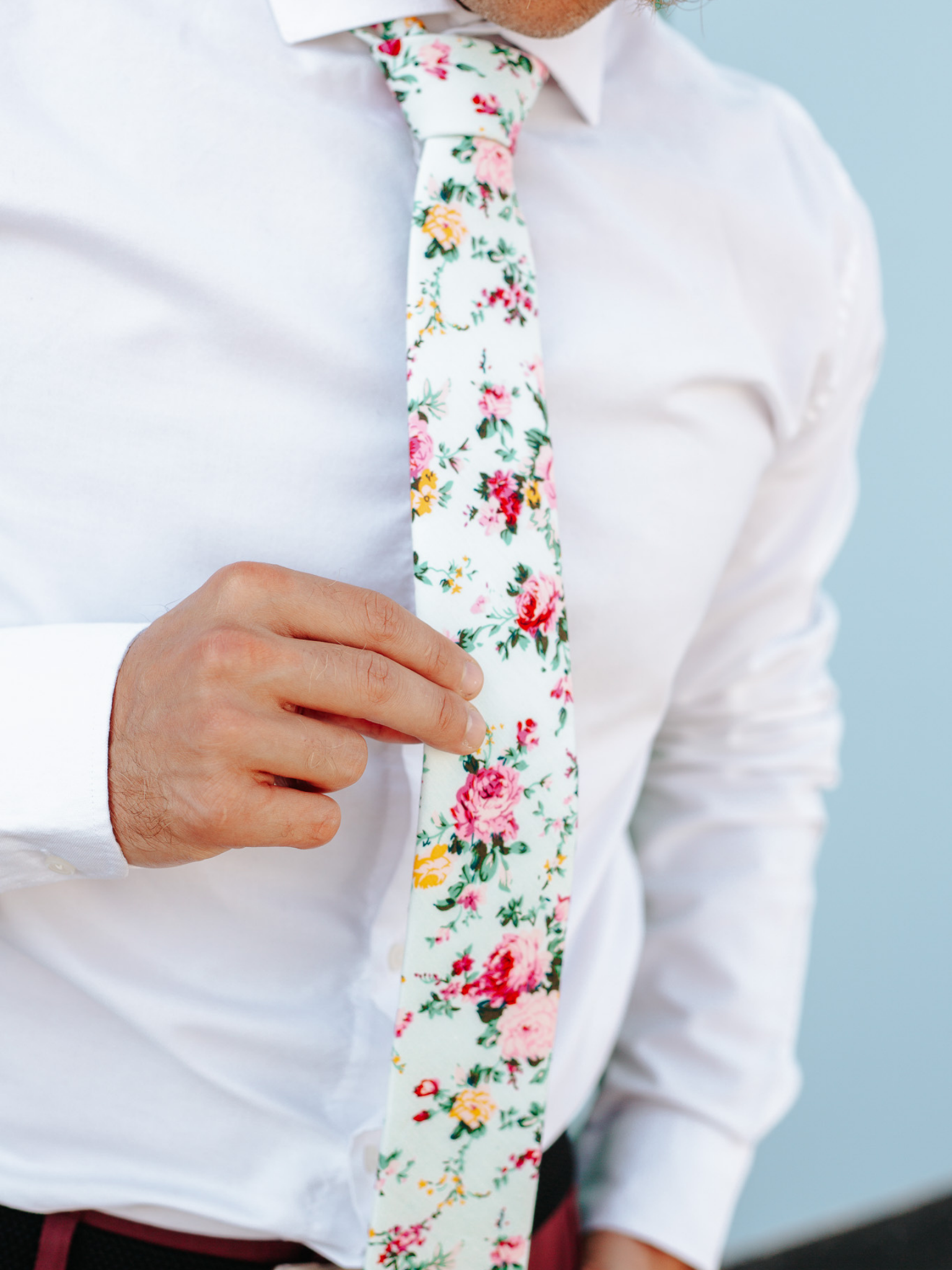 A close up of a man wearing a mint and pink flower cotton skinny tie for weddings, grooms, and groomsmen.