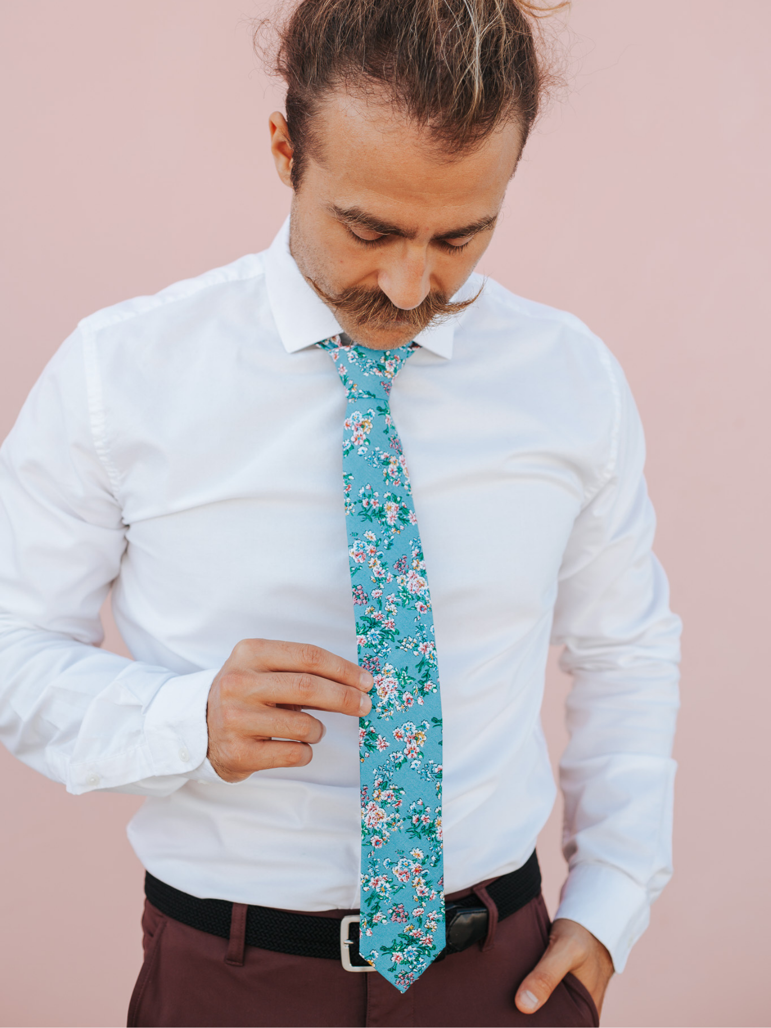 A close up of a man wearing a blue and purple flower cotton skinny tie for weddings, grooms, and groomsmen.