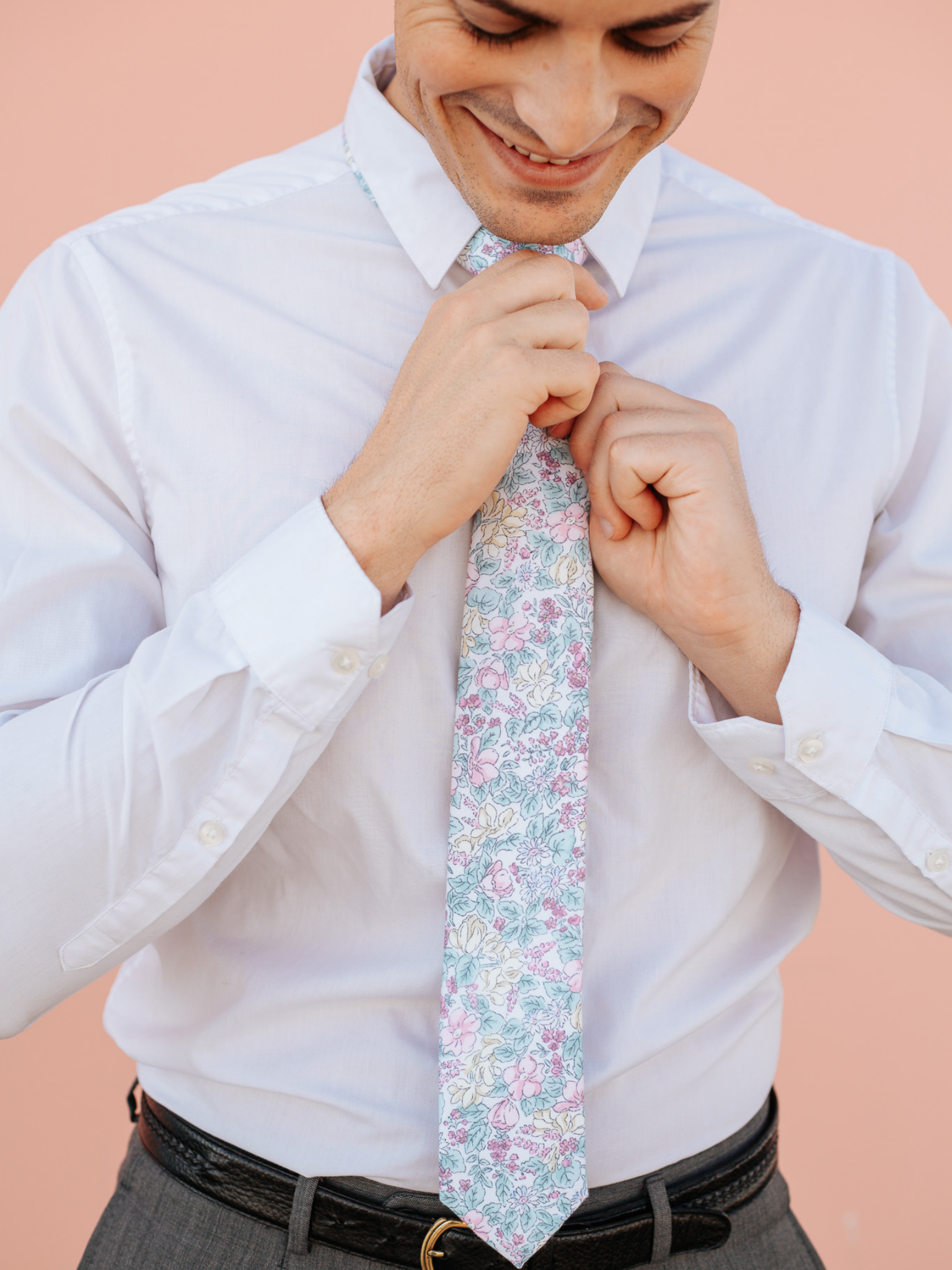 A close up of a man wearing a pastel blue and purple flower cotton skinny tie for weddings, grooms, and groomsmen.