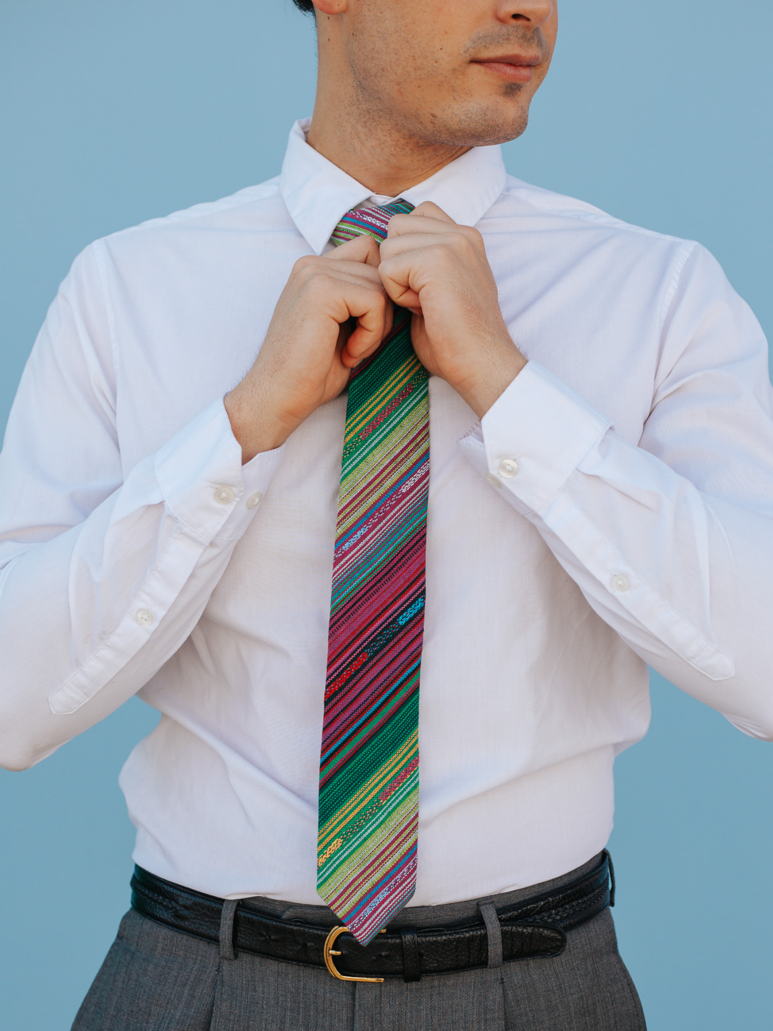 A close up of a man wearing a green and purple striped cotton skinny tie for weddings, grooms, and groomsmen.