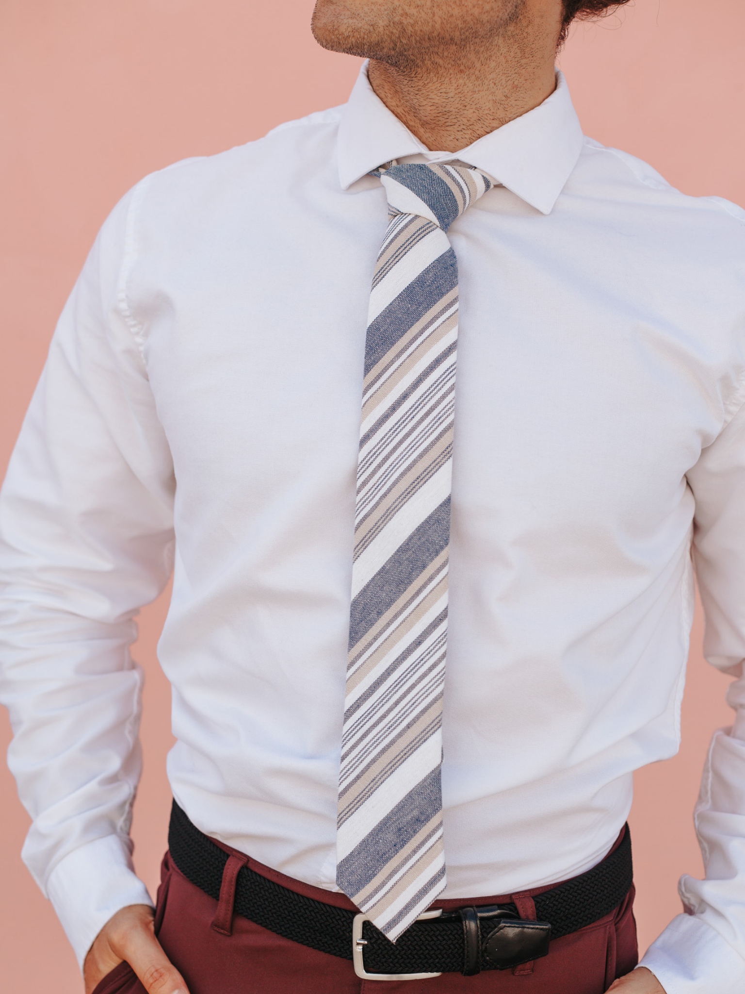 A close up of a man wearing a blue, white, and gold striped cotton skinny tie for weddings, grooms, and groomsmen.