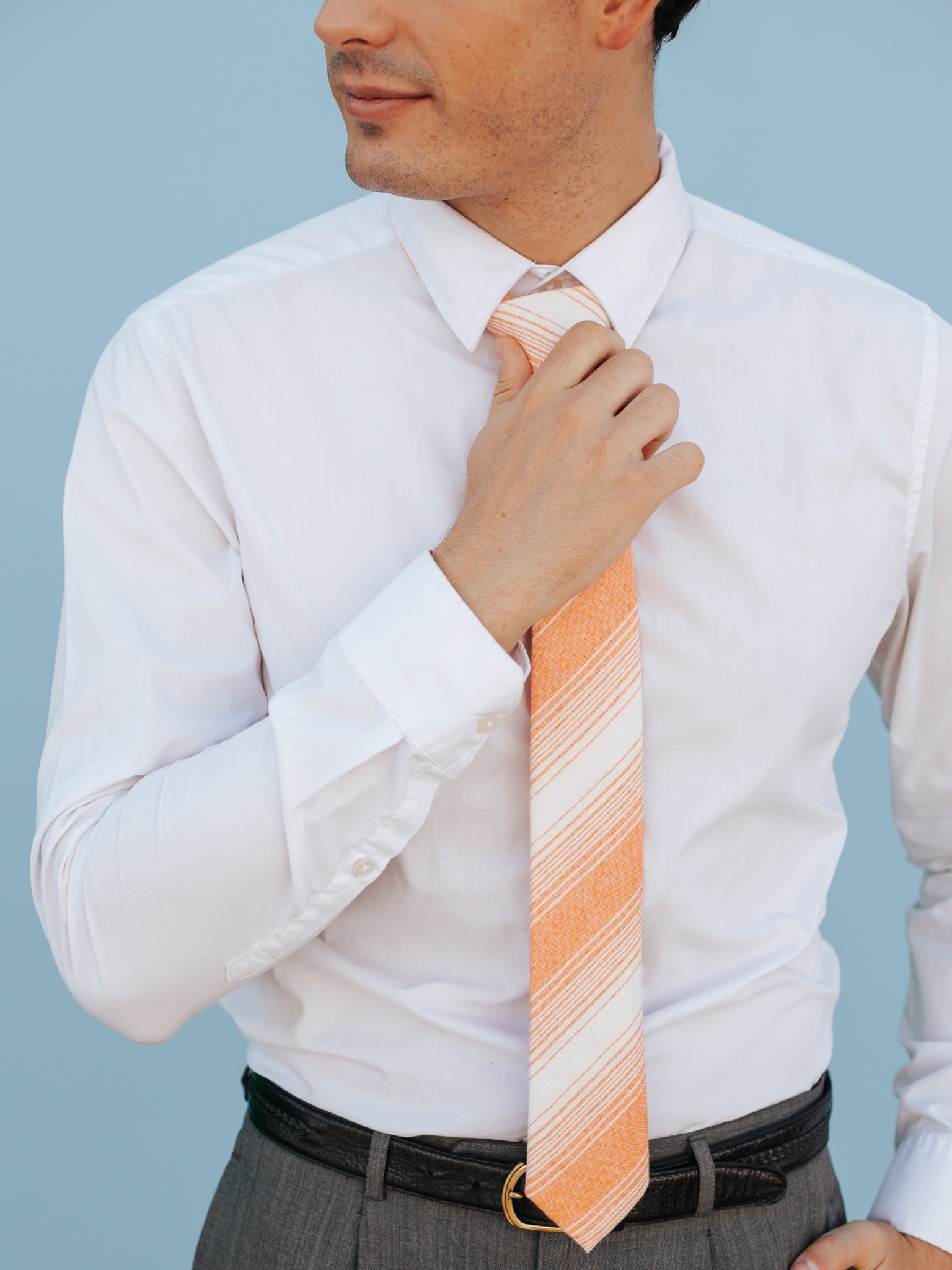 A close up of a man wearing a orange and cream striped cotton skinny tie for weddings, grooms, and groomsmen.