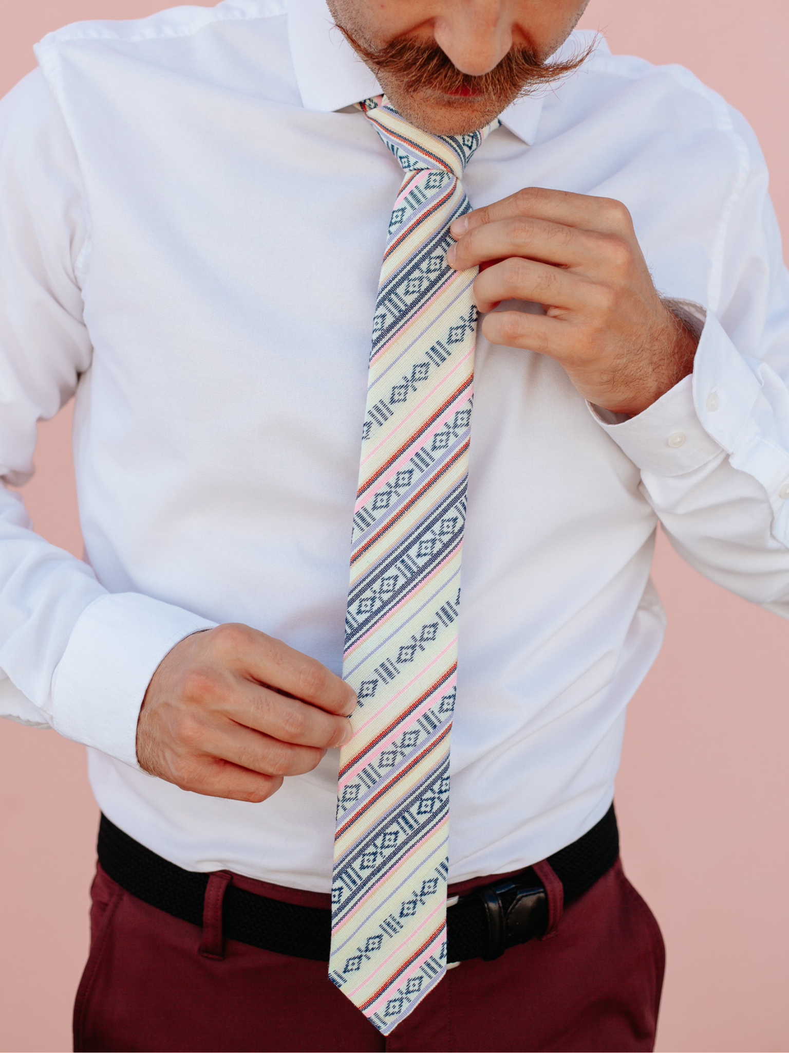 A close up of a man wearing a white, red and black striped cotton skinny tie for weddings, grooms, and groomsmen.