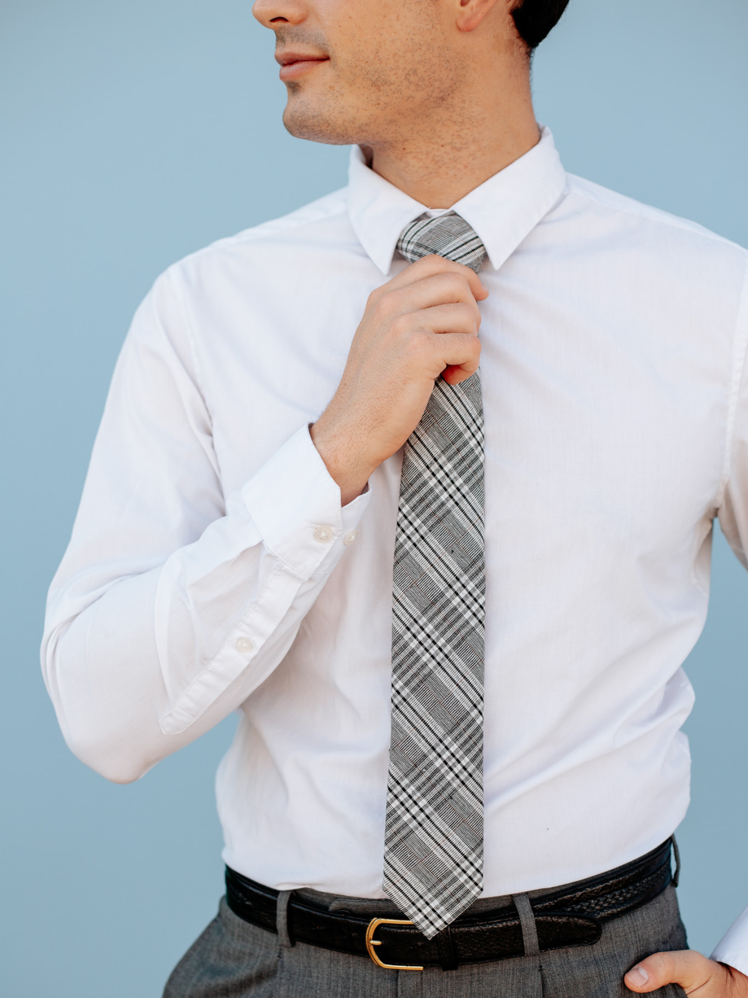 A close up of a man wearing a black and white plaidcotton skinny tie for weddings, grooms, and groomsmen.