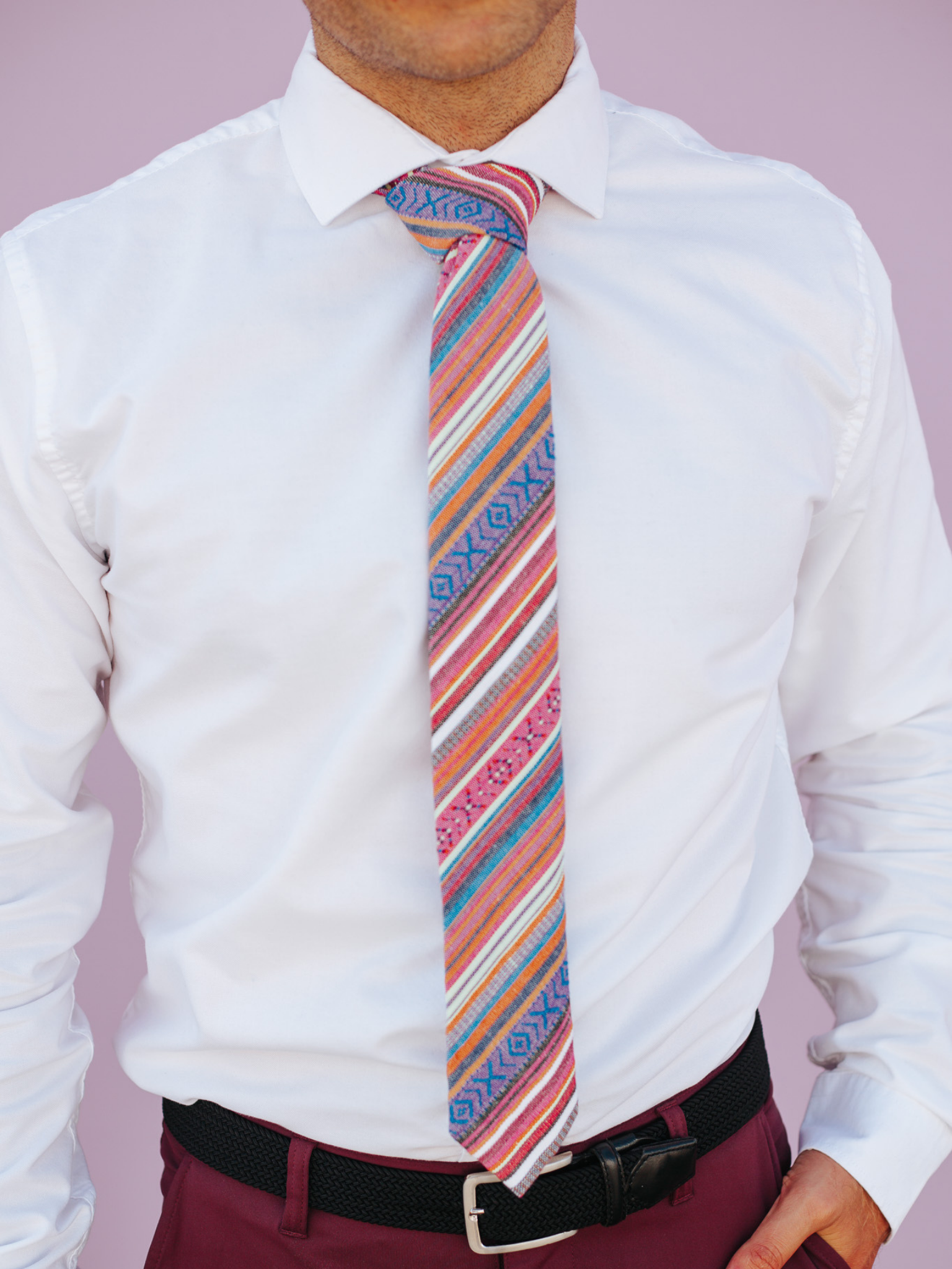 A close up of a man wearing a blue and orange striped cotton skinny tie for weddings, grooms, and groomsmen.