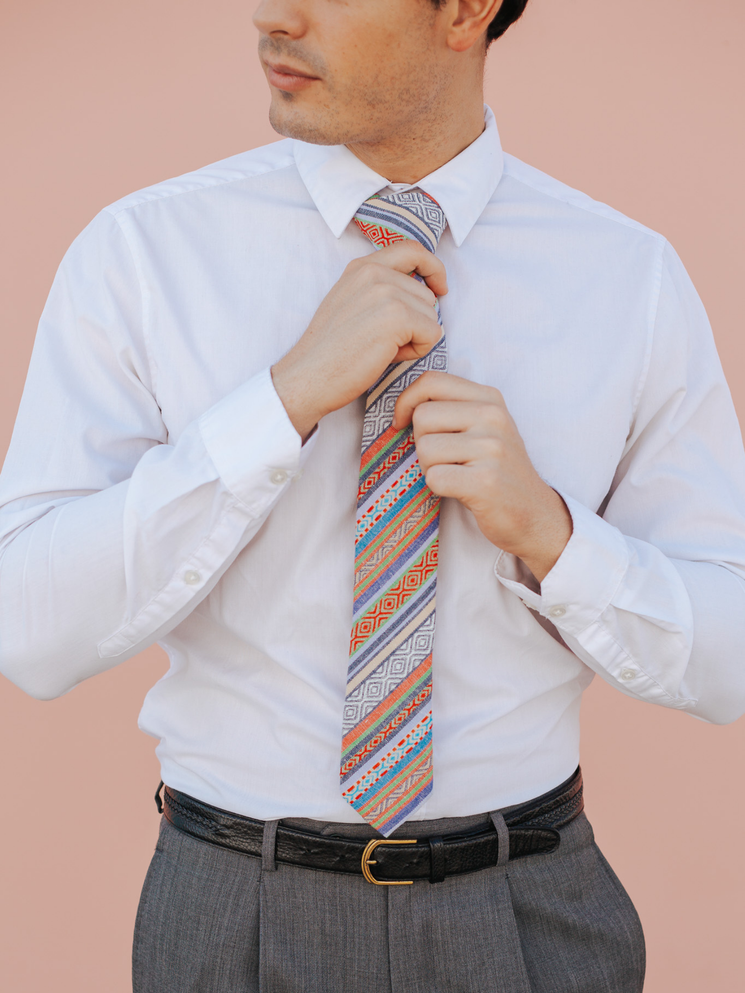 A close up of a man wearing a red, green, and blue striped cotton skinny tie for weddings, grooms, and groomsmen.