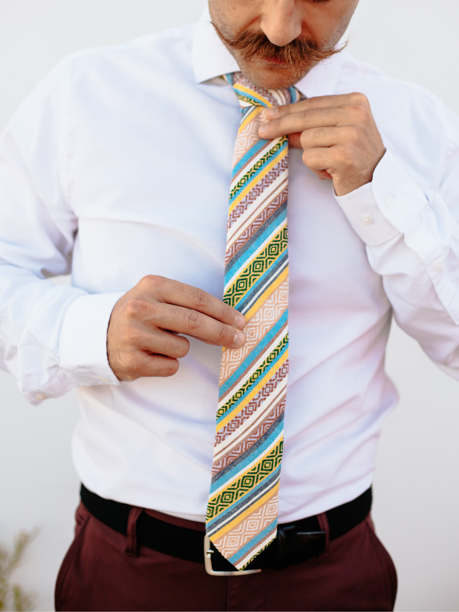 A close up of a man wearing a yellow and blue striped cotton skinny tie for weddings, grooms, and groomsmen.