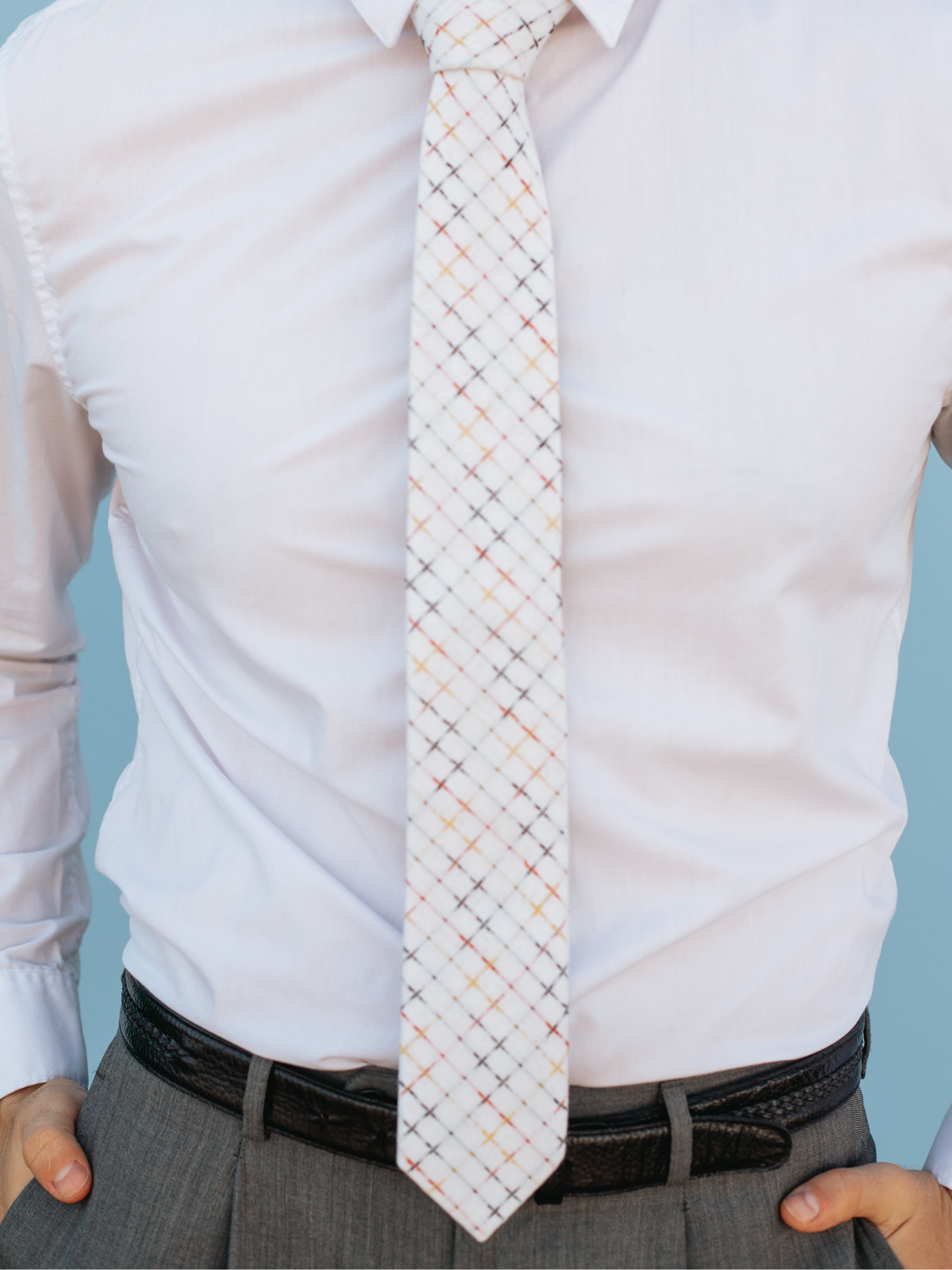 A close up of a man wearing a white, black, and red striped cotton skinny tie for weddings, grooms, and groomsmen.