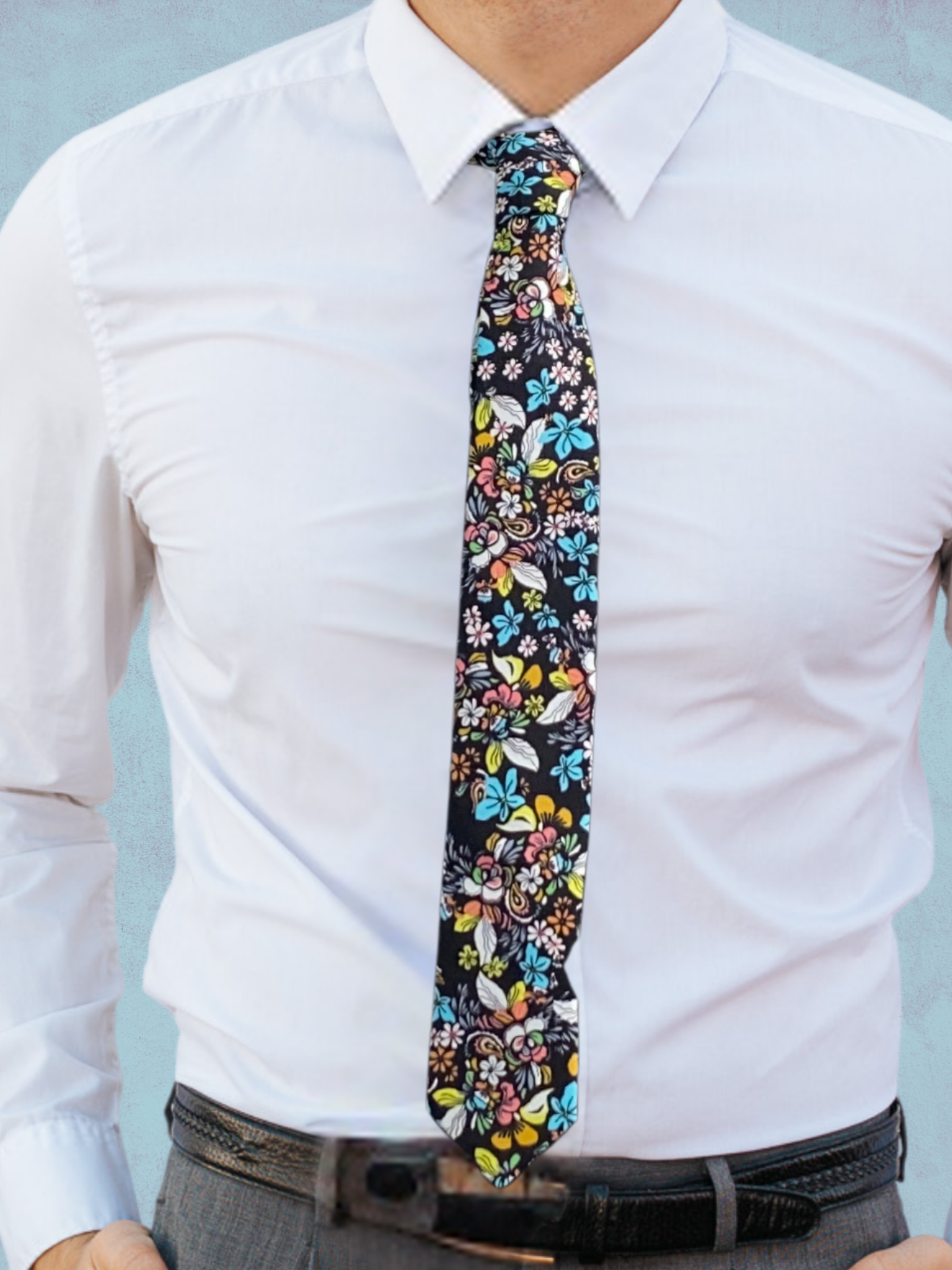 A close up of a man wearing a black, blue, yellow, green, and pink flower cotton tie for weddings grooms and groomsmen.