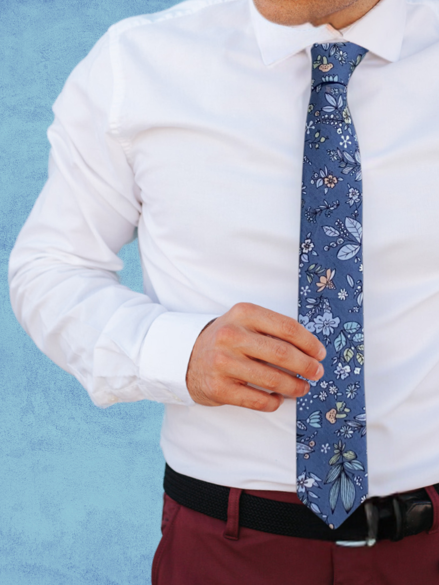 A close up of a man wearing a deep blue, pale blue, green, and pink flower cotton tie for weddings grooms and groomsmen.