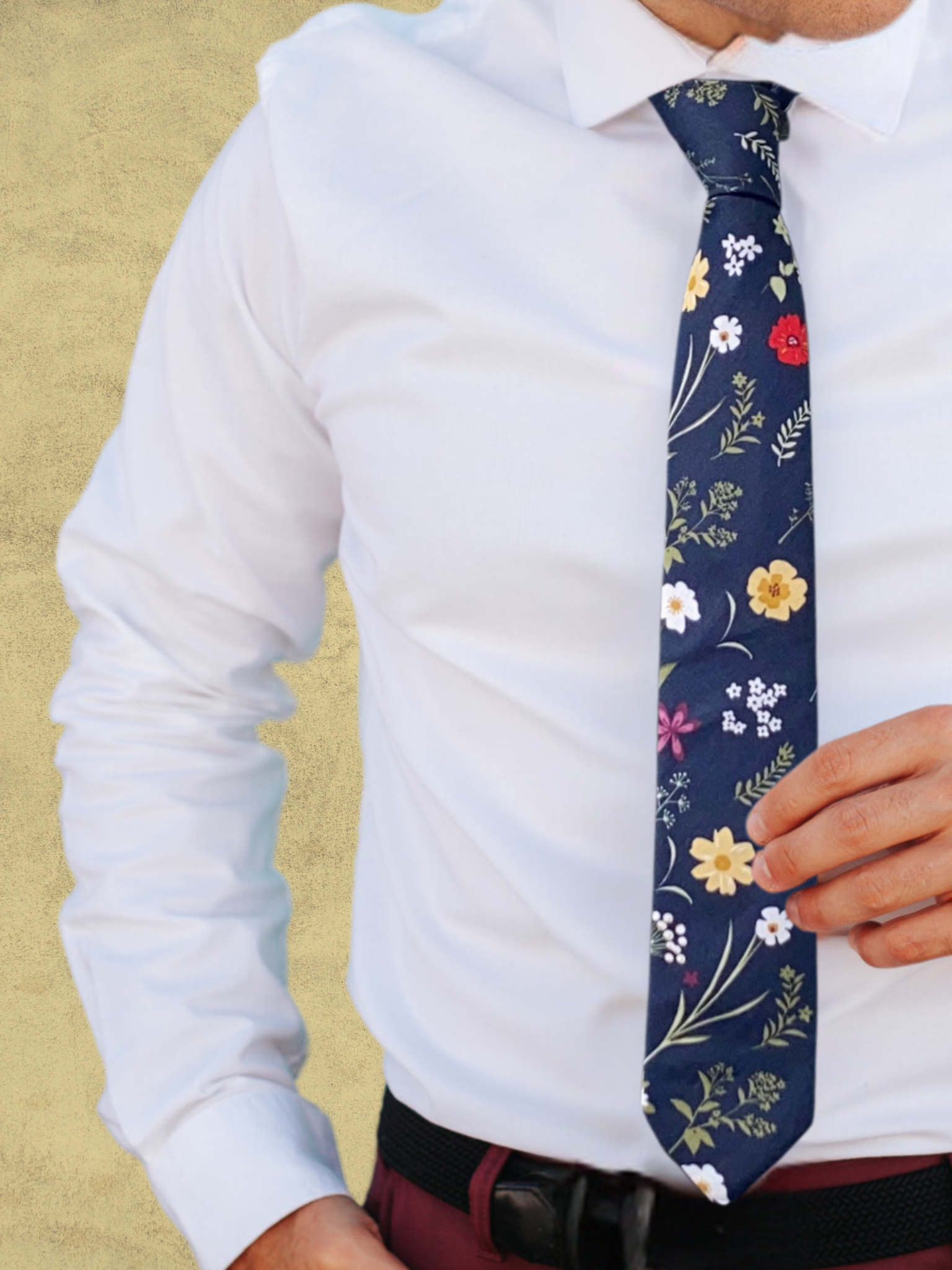 A close up of a man wearing a navy blue, green, white, yellow, and red flower cotton tie for weddings grooms and groomsmen.