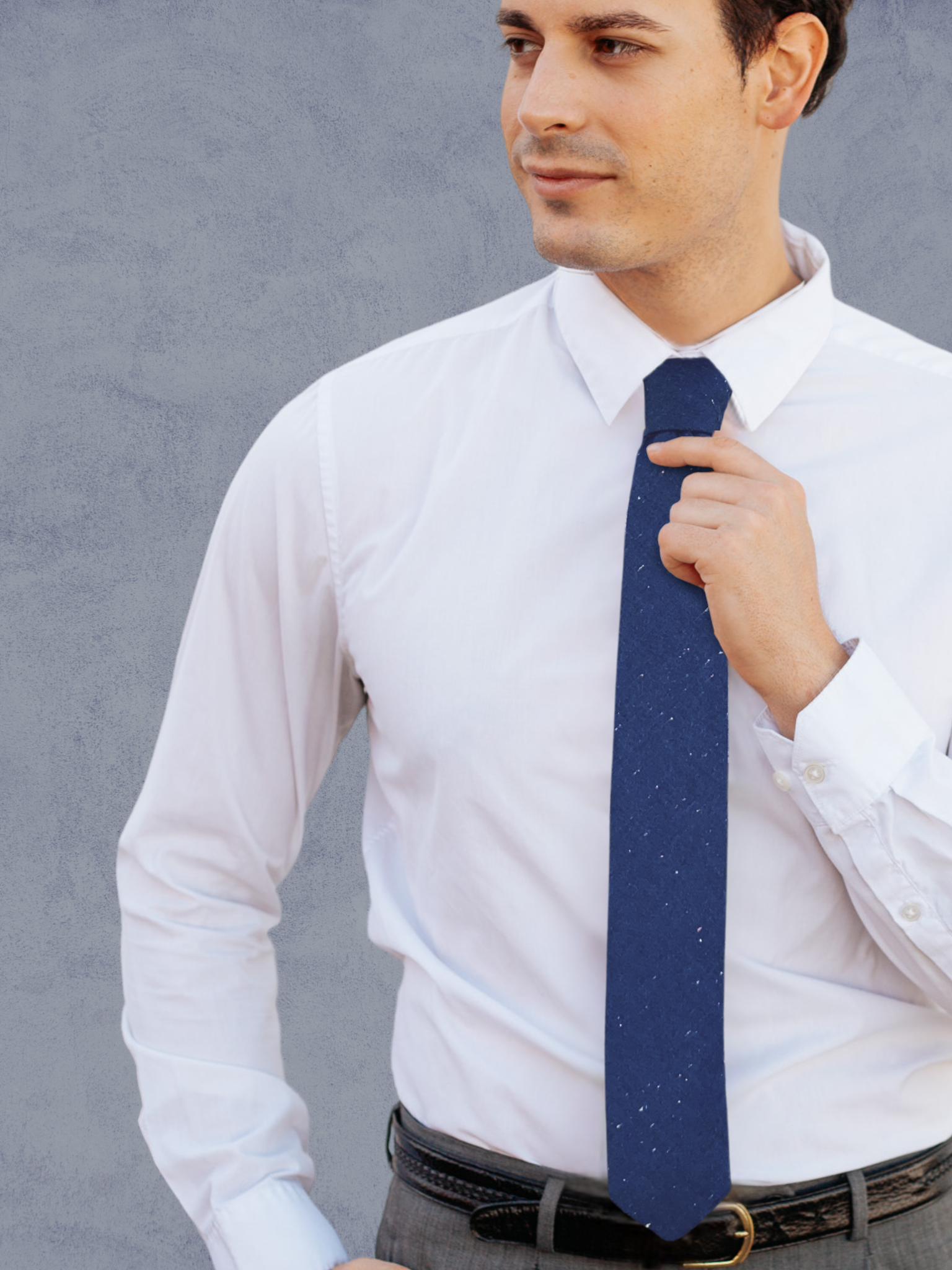 A close up of a man wearing a multicolor and navy solid speckled cotton tie for weddings, grooms, and groomsmen.