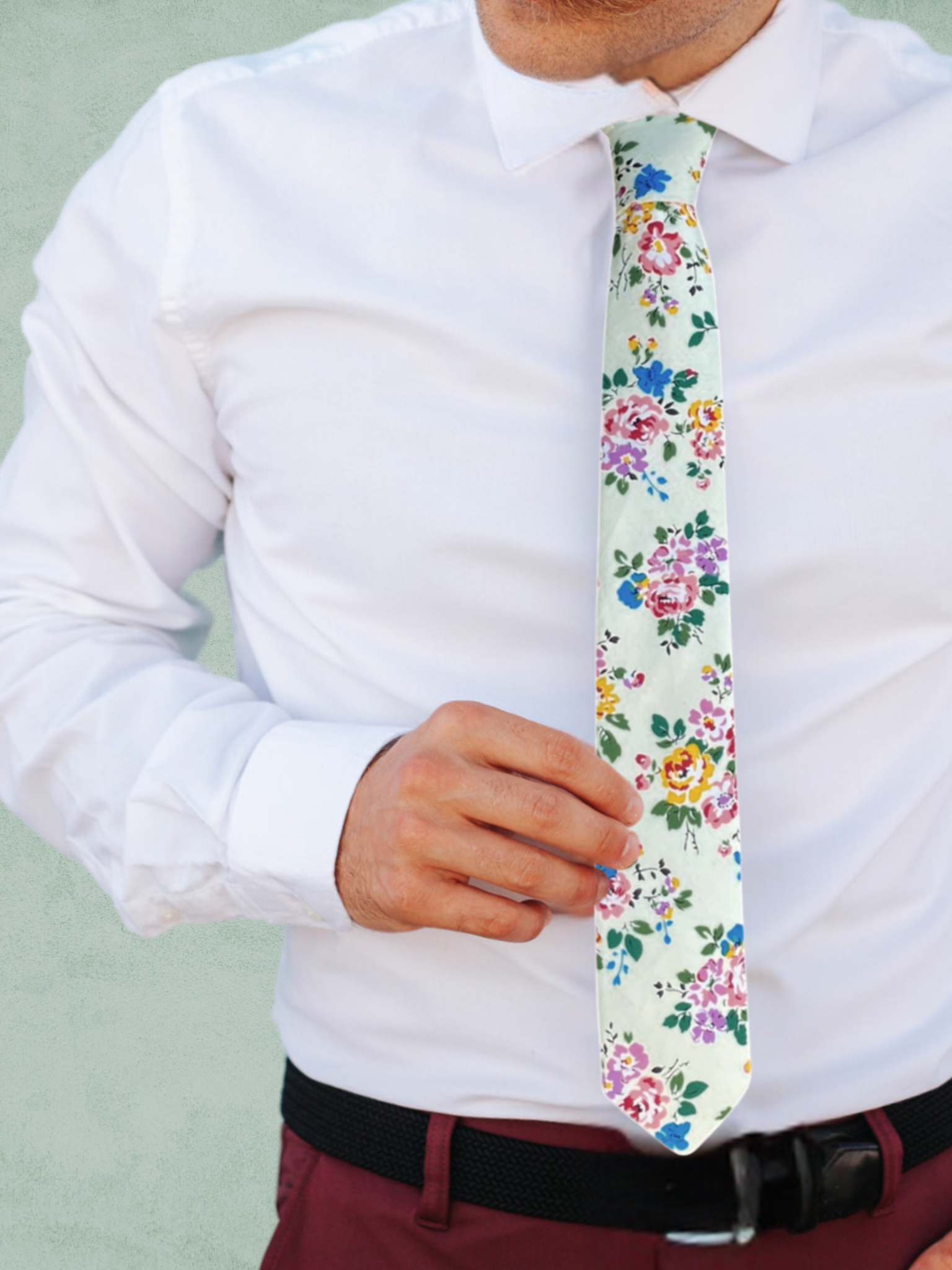 A close up of a man wearing a dark green, blue, yellow, and lavender flower cotton tie for weddings, grooms, and groomsmen.