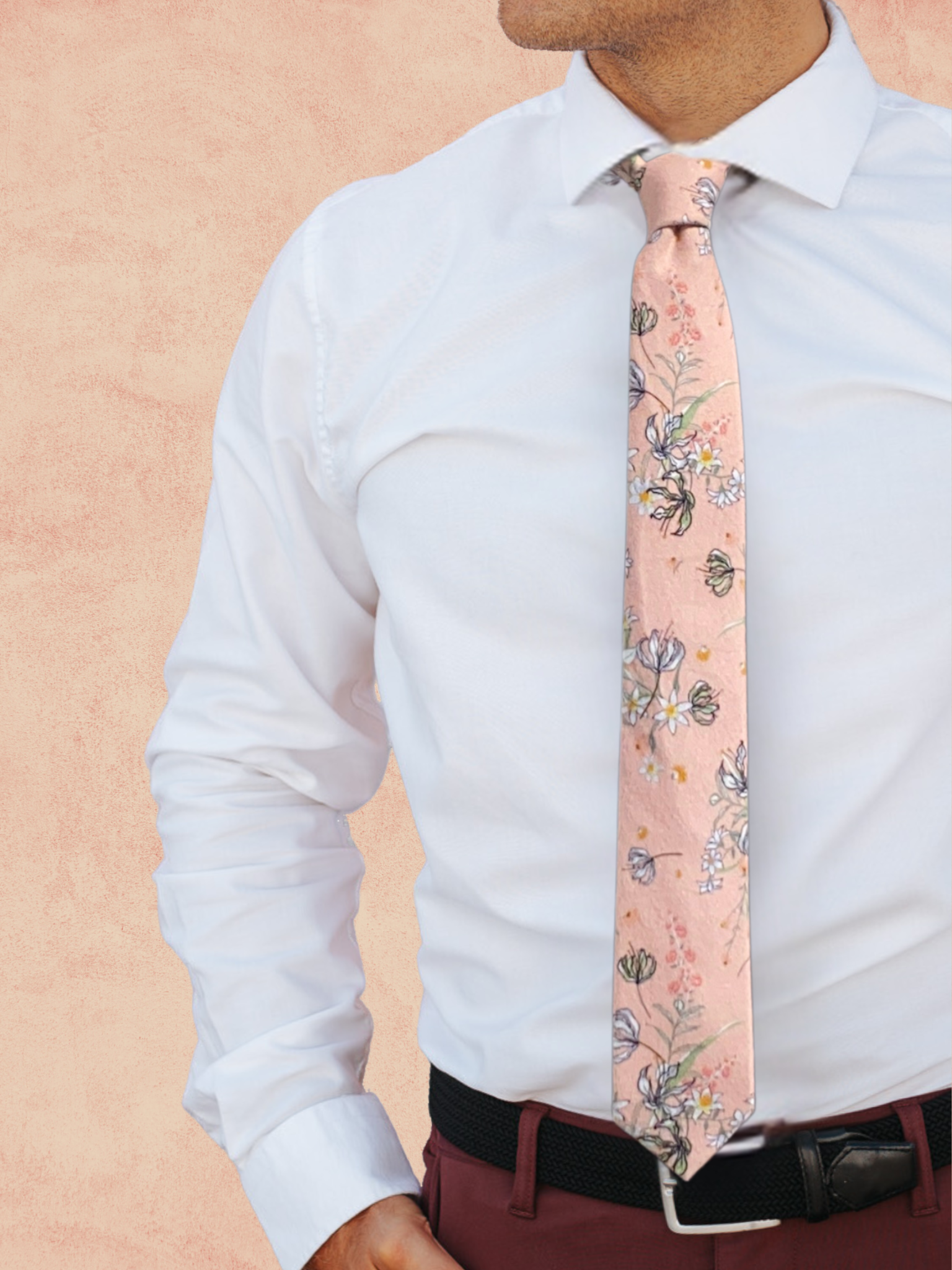 A close up of a man wearing a salmon, yellow, white, pink, and green flower cotton tie for weddings grooms and groomsmen.