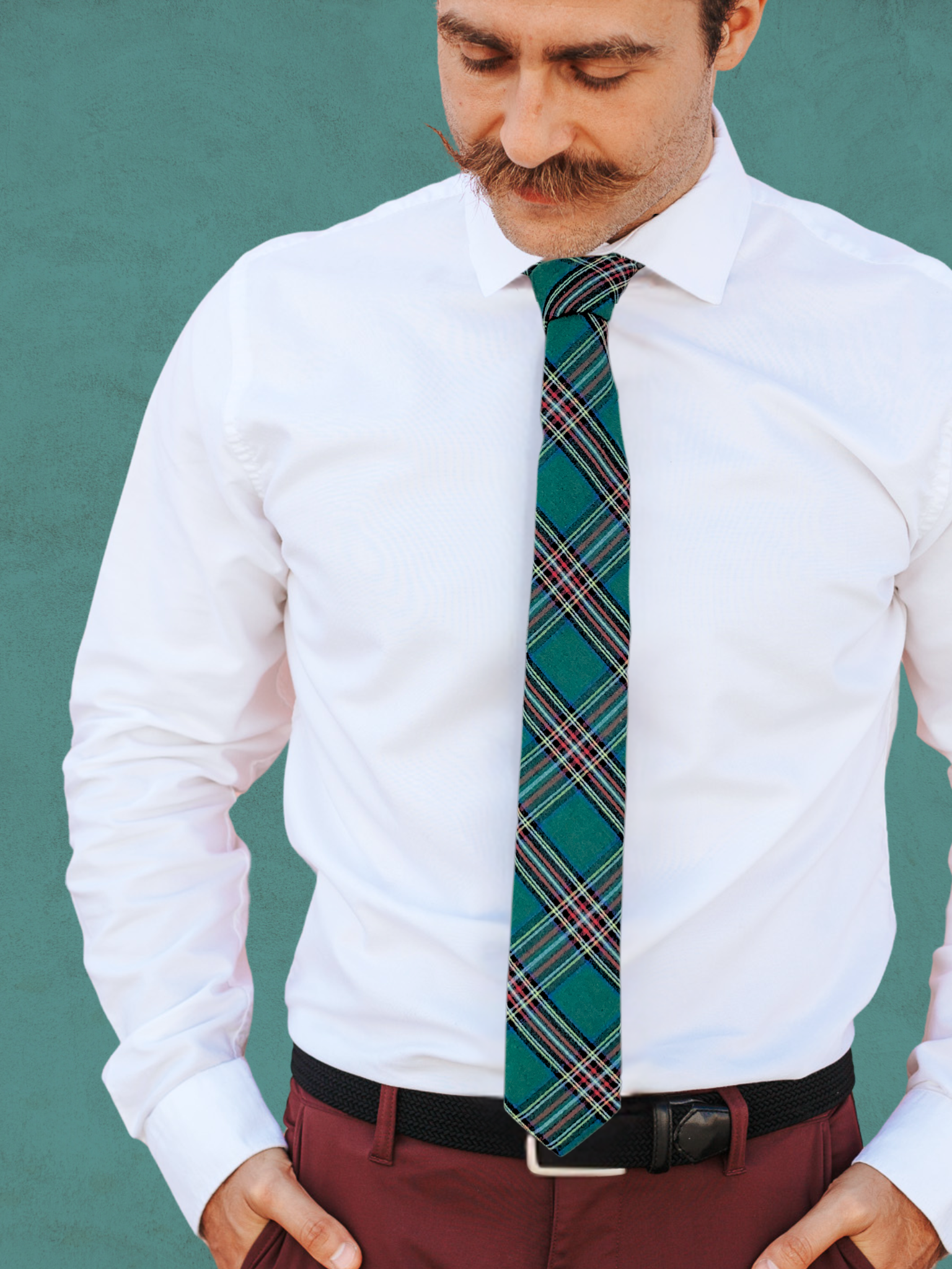 A close up of a man wearing a red, white, yellow, and dark green plaid cotton tie for weddings, grooms, and groomsmen.